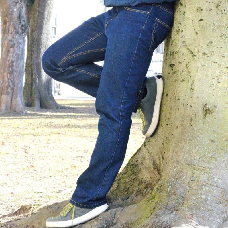Model leans with durable classic jeans against tree